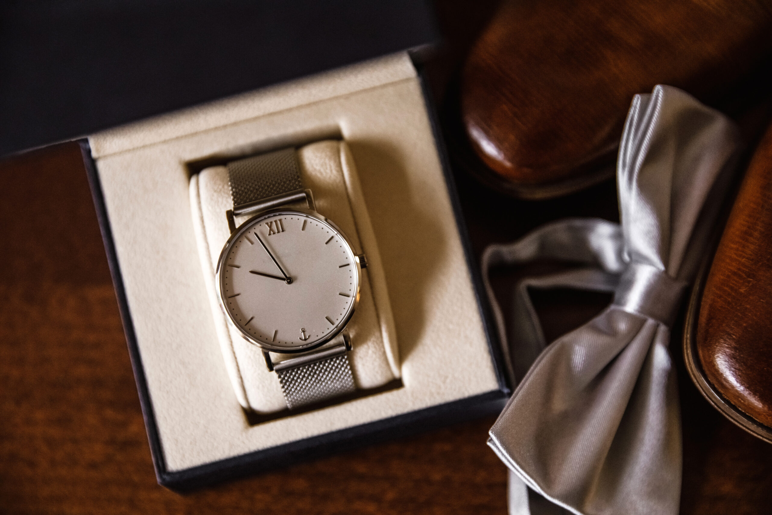 Men's watch on a table with shoes and a butterfly. Wedding accessories on wooden brown background. traditional idea composition. Accessories for a businessman